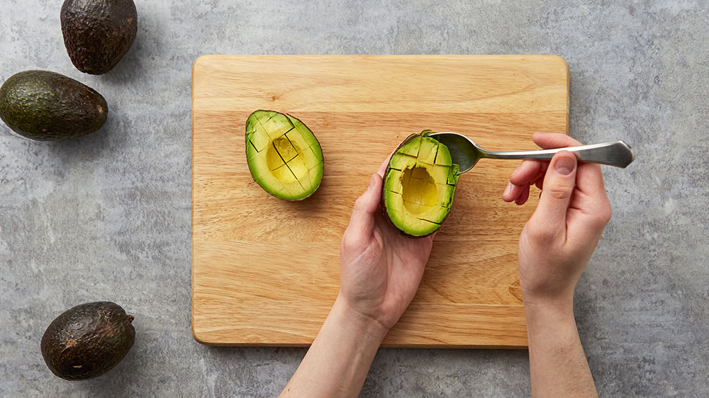 using a small knife to make horizontal and vertical slices across the avocado