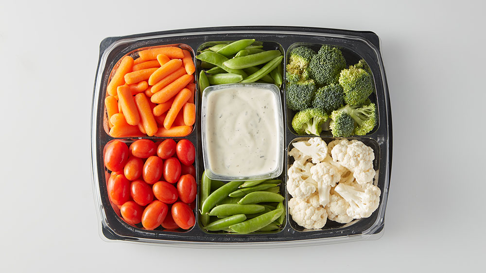 store bought veggie tray with dip, carrots, tomatoes, peas, cauliflower and broccoli. 