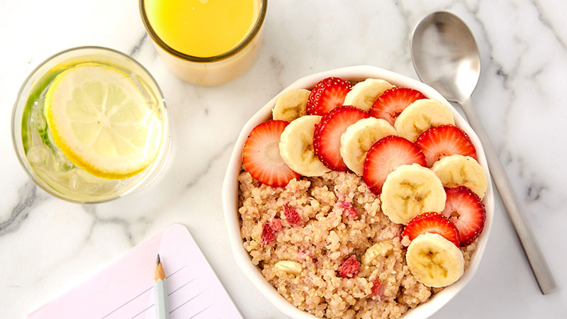 Lemon water, orange juice, Strawberry-Banana Breakfast Quinoa, spoon, notepad and pencil