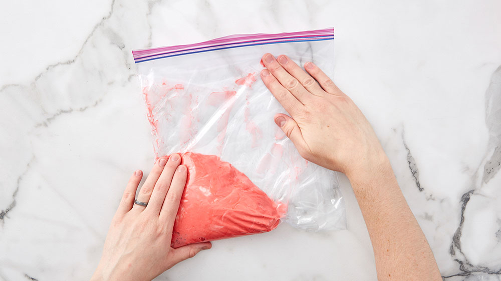 smoothing out ziploc bag with frosting in it