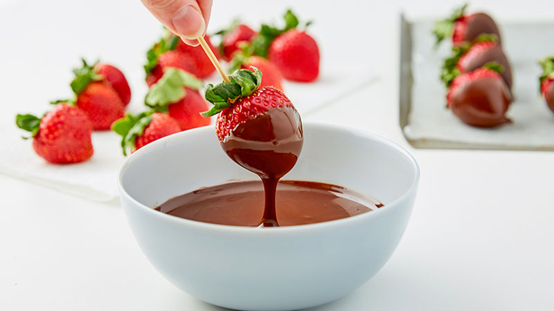 Dipping a strawberry into a bowl of melted chocolate