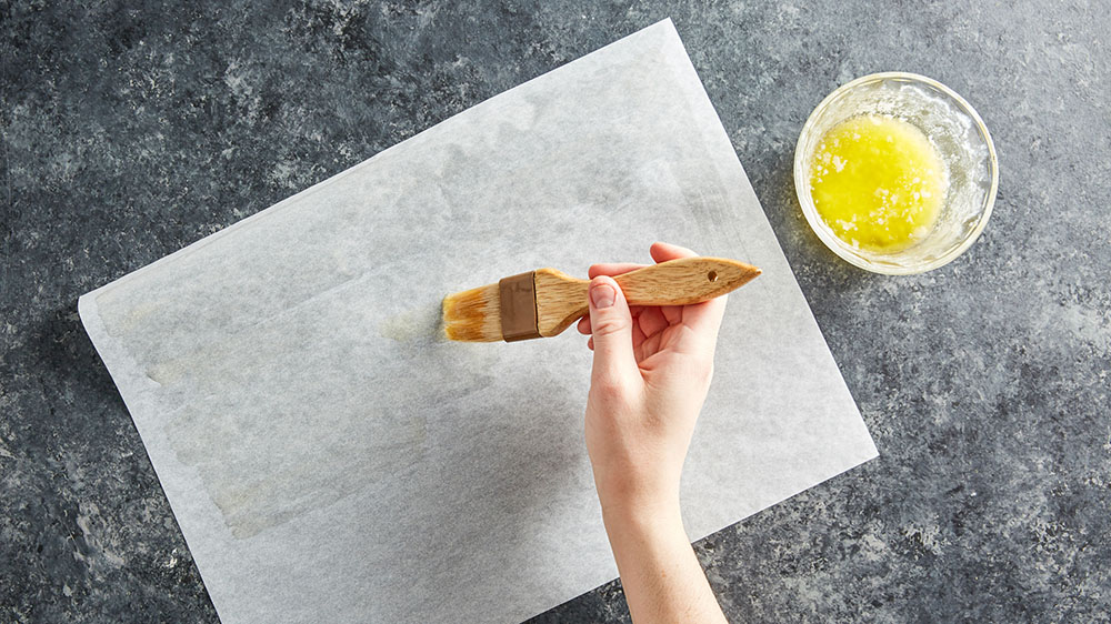 brushing butter on parchment paper