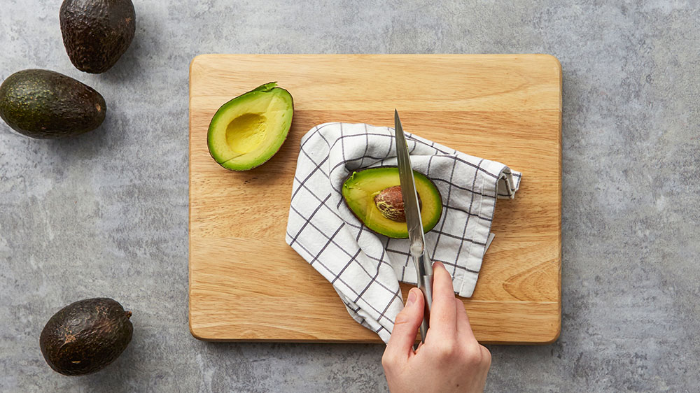 With a heavy, sharp knife, swiftly and carefully bring the blade of the knife to the avocado pit
