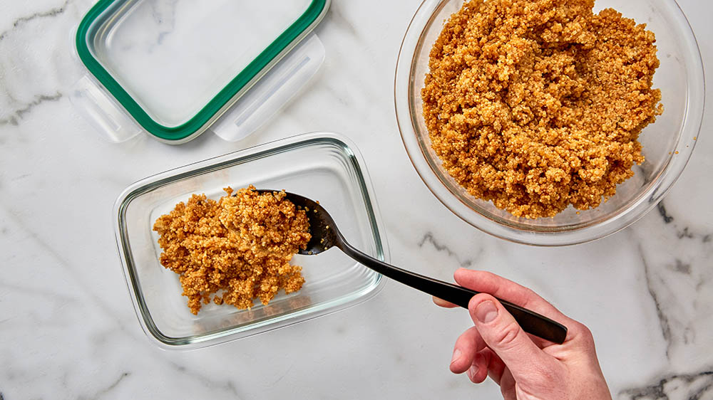 spooning food into meal prep containers