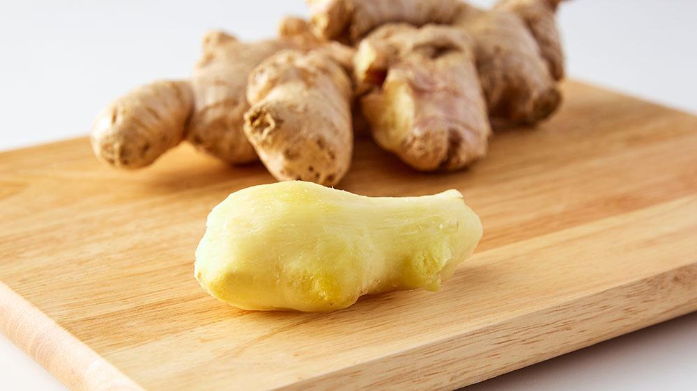pile of unpeeled ginger and one piece of peeled ginger