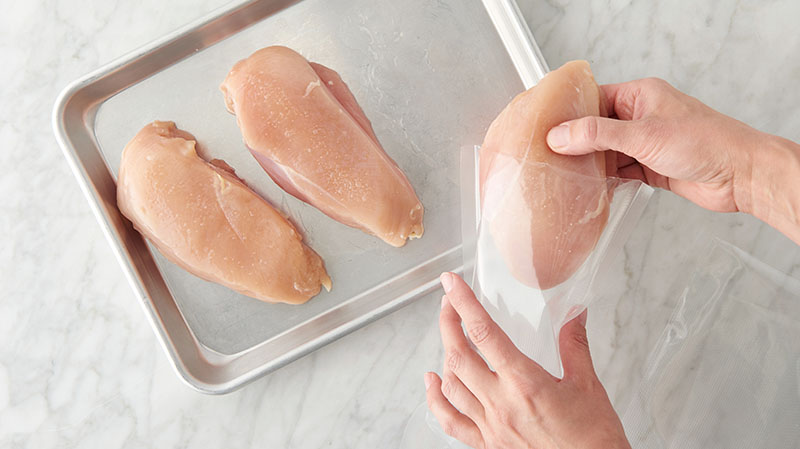 Place raw chicken breasts inside a plastic bag
