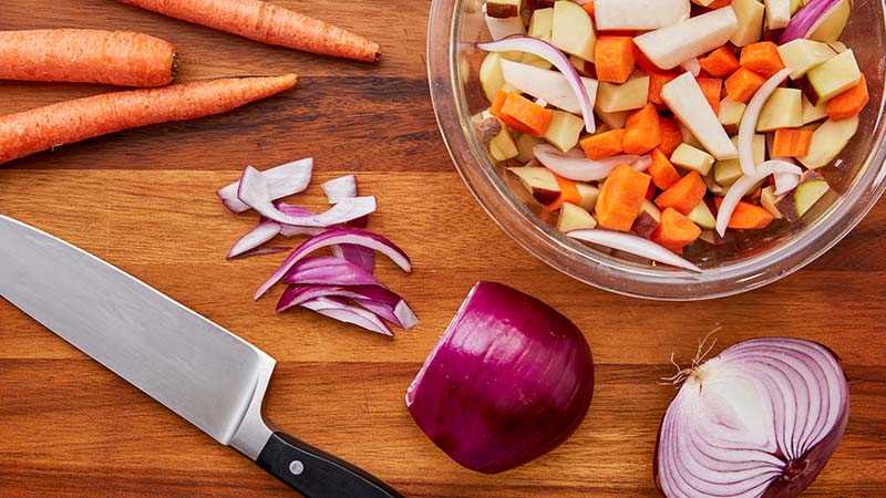 Cutting board, knife, chopped carrots onions